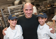 FIU-0164-WF10 - Celebrity Chef Michael Symon, with FIU School of Hospitality student volunteers Ayelen Ferrer, right, and Soraya Doura while getting ready for Burger Bash at the Ritz-Carlton South Beach